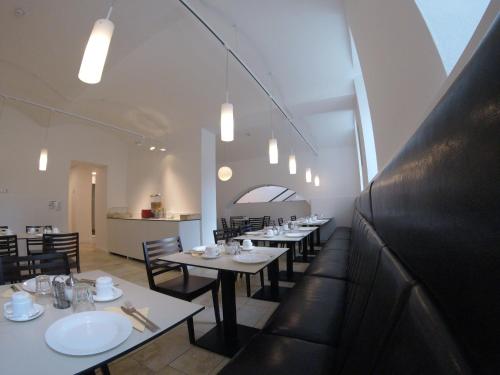 a dining room with white tables and black chairs at Hotel Aton in Graz