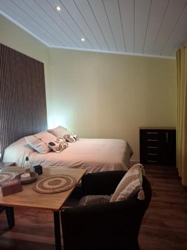 a bedroom with a bed and a table with a couch at My Refugio Wet Wet in Puerto Montt