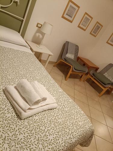 a bedroom with a bed with two chairs and towels at La casetta di Nonno Carlo a due passi dall'ospedale in Torrette