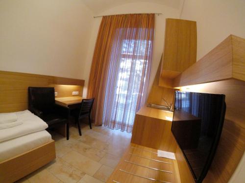 a room with a bed and a desk and a table at Hotel Aton in Graz