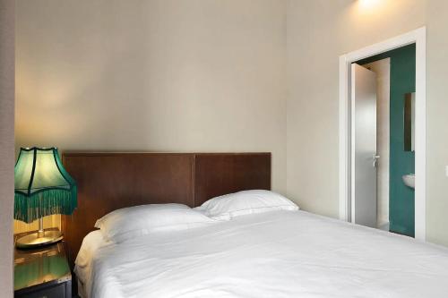 a bedroom with a bed with a wooden headboard and a lamp at Mistral Holidays - Minisuite Marina in Marina di Carrara