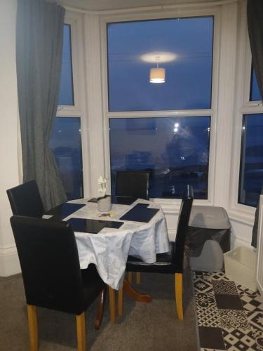 a dining room table with chairs and a large window at Rowntree Seaview Holiday Apartments in Bridlington
