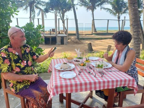 two older women sitting at a table eating food at Roy Villa Beach Front in Padagala