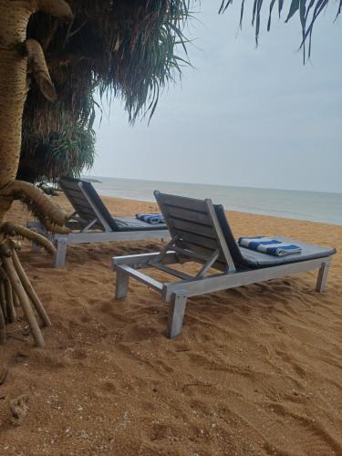 two lounge chairs on a beach with the ocean at Roy Villa Beach Front in Padagala