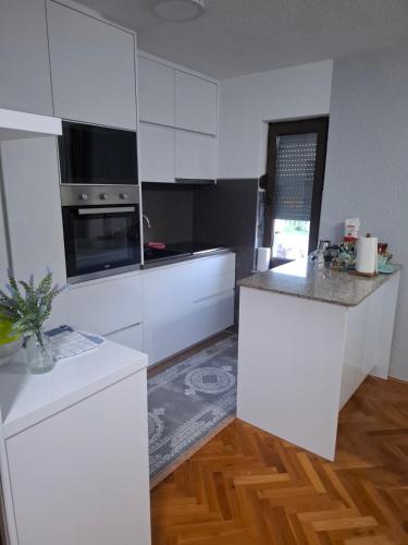 a kitchen with white cabinets and a counter top at Apartman - TAHRIC in Bihać