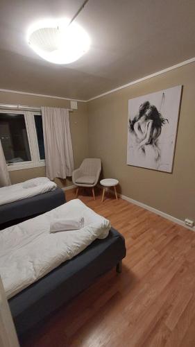 a bedroom with two beds and a chair in it at Lyngen Apartments in Lyngseidet