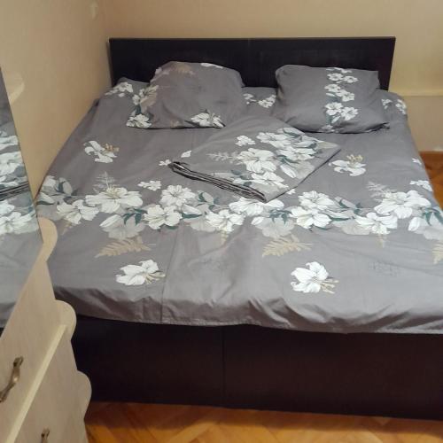 a bed with a blanket with white flowers on it at Guest House Edem in Tbilisi City