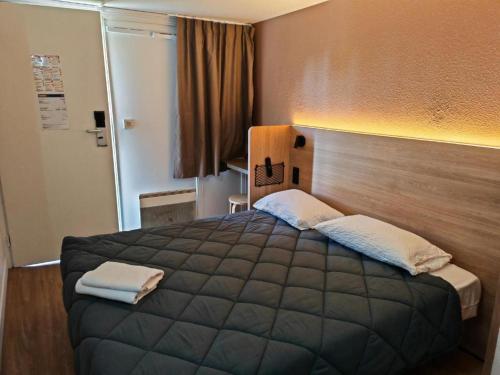 a bedroom with a large bed with a wooden headboard at HOTEL PREMIERE CLASSE Rouen Sud Oissel in Saint-Étienne-du-Rouvray