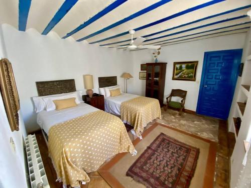 a bedroom with two beds and a blue and white ceiling at Finca La Alcolehuela in Santa Elena