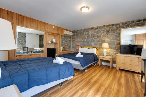 a bedroom with two beds and a stone wall at Le Cavalier du Moulin - M11 in Quebec City