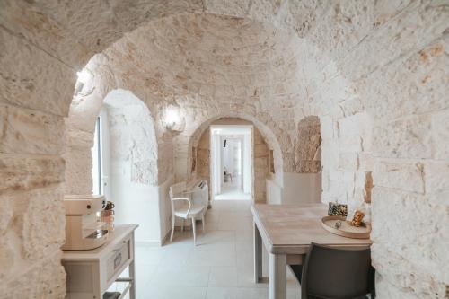 a kitchen with a table and a stone wall at Trullo Alisia - TrulloExperience in Putignano