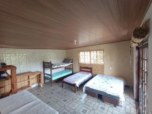 a room with two beds and a bench in it at Chácara c piscina in Cotia