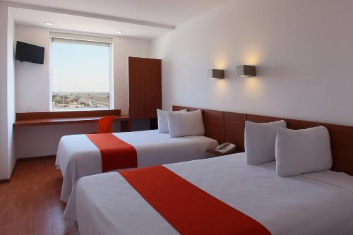 a hotel room with two beds and a window at One Queretaro Aeropuerto in Querétaro