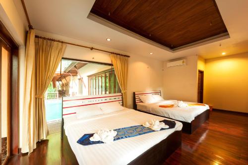 a bedroom with two beds and a large window at Palms Hill Resort in Phangnga