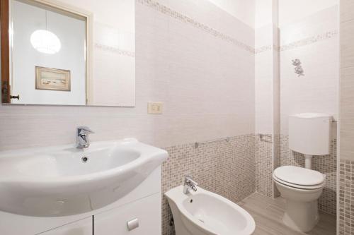 a white bathroom with a sink and a toilet at Hotel Torre in Viareggio