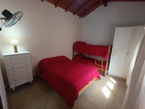 a small bedroom with a red bed and a dresser at Deptos Pablos, Apto No 4 in Villa Gesell