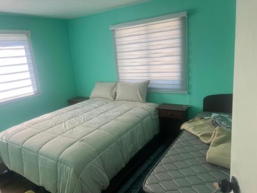 a bedroom with blue walls and a bed and two windows at CASA DEL CENTRo in Quellón