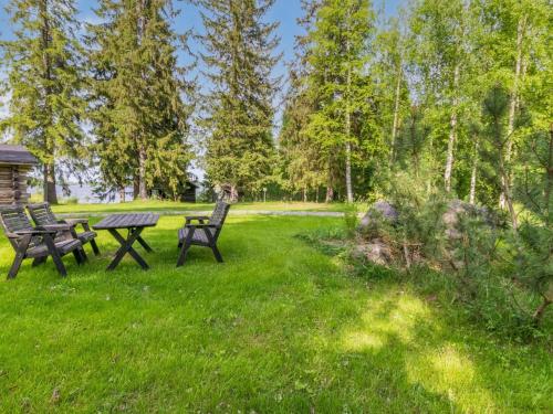 two benches and a picnic table in a park at Holiday Home Kelo-kolo by Interhome in Iisalmi