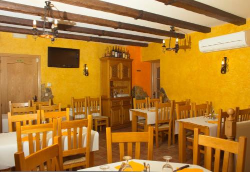 um restaurante com paredes amarelas, mesas e cadeiras em Hostal El Bodegon em Ateca