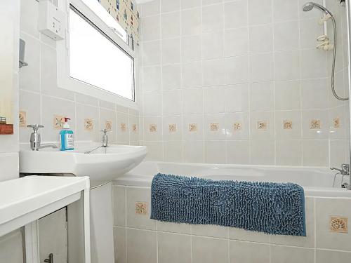 a white bathroom with a sink and a bath tub at 21 The Glade in Bude