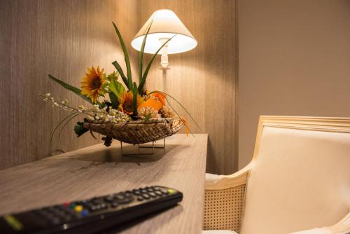 a remote control sitting on a table with a basket of flowers at Albergo Grappolo D'oro in Montebelluna