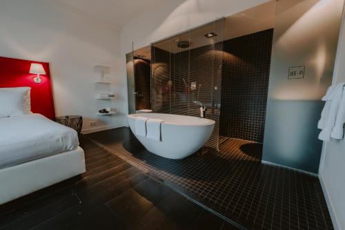 a bathroom with a tub and a bed and a shower at Boutique Hotels MANNA & Blue in Nijmegen