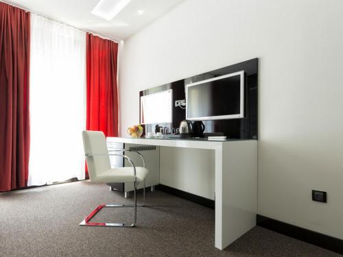 a room with a desk with a television and a chair at Nova City Garni Hotel Signature Collection in Belgrade
