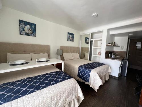 a hotel room with two beds and a table at SKY INN Oficial Acapulco Suites & Condo Mediterrane in Acapulco