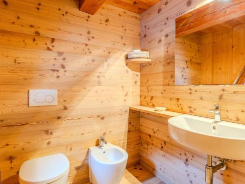 a bathroom with wooden walls and a toilet and a sink at Chalet Maset Pozzati by Interhome in Bresimo