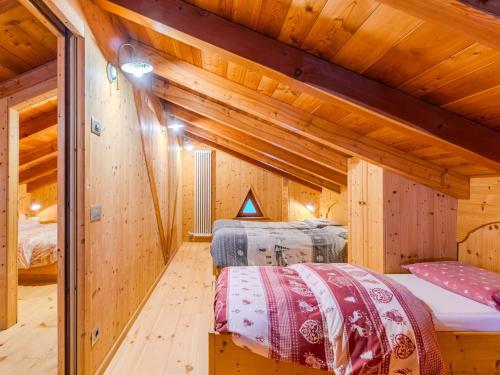 two beds in a room with wooden walls at Chalet Maset Pozzati by Interhome in Bresimo