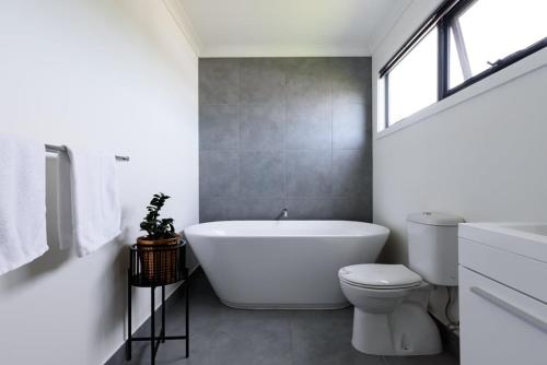 a bathroom with a white tub and a toilet at Modern Newnham Retreat in Newnham