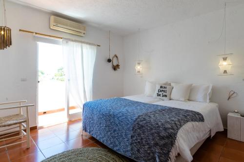 a white bedroom with a bed and a window at Utopia in Aljezur