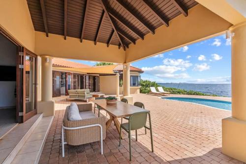 eine Außenterrasse mit Tisch und Stühlen und ein Pool in der Unterkunft Casa Tranquilidad in Willemstad