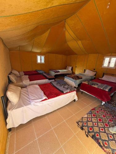 a room with a bunch of beds in a tent at Mustapha Camp Merzouga in Merzouga