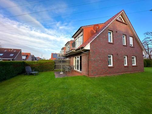 a large brick house with a grass yard at Möwennest in Norden