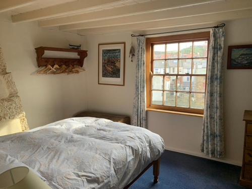 a bedroom with a bed and a window at Old Jack's Cottage, Staithes in Staithes