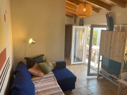 a living room with a blue couch and a television at Coastal Vineyard Hideaway in Torres Vedras