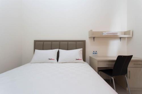 a bedroom with a bed and a desk and a chair at RedDoorz Plus near Siloam Karawaci in Tangerang
