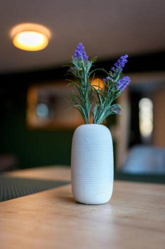 a white vase with purple flowers sitting on a table at Das Chalet in Himmelkron