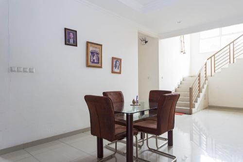 a dining room with a glass table and brown chairs at RedDoorz Plus near Siloam Karawaci in Tangerang