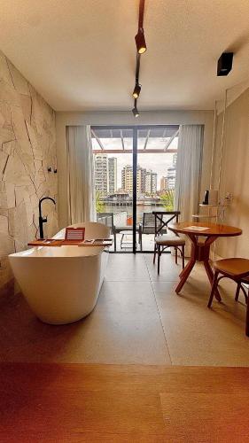 a large room with a bath tub and a table at Azurine Pousada in Passo de Torres