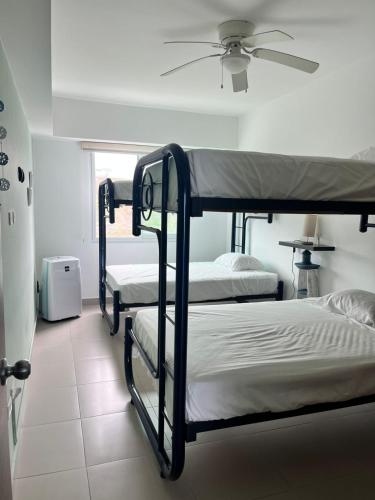 two bunk beds in a room with a ceiling fan at Departamento frente al mar - Resort Playa Azul in Tonsupa