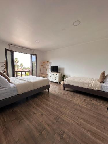 two beds in a large room with wooden floors at La Casona Papudo in Papudo