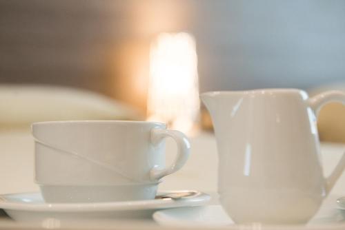 two white cups and saucers sitting on a table at Albergo Grappolo D'oro in Montebelluna