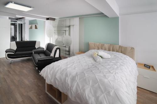 a bedroom with a white bed and two chairs at Designpension Idyll Nr2 Hotel Garni in Wernigerode