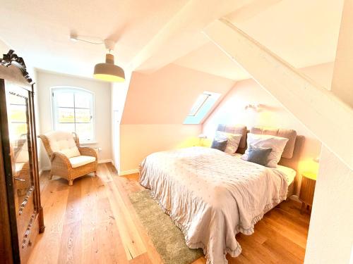 a bedroom with a bed and a chair at Boddenhuus - Traumhaus mit Steg und Boot in Zudar