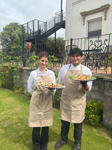two people in aprons holding plates of food at Chase Hotel in Whitehaven