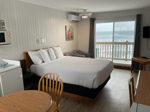 a hotel room with a bed and a balcony at Motel Carleton Sur Mer in Carleton-sur-Mer