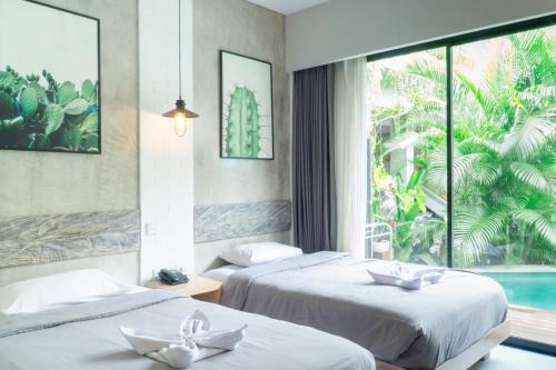 two beds in a hotel room with a window at Gemini Star Hotel Kuta in Kuta