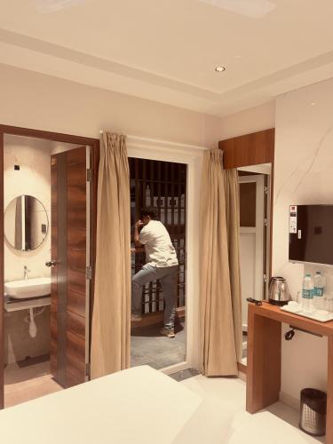 a man standing in a bathroom looking in a mirror at Hotel Liora Suites in Bangalore